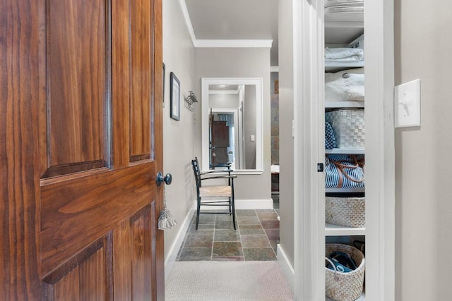 foyer featuring baseboards, crown molding, and dark stone finish floors