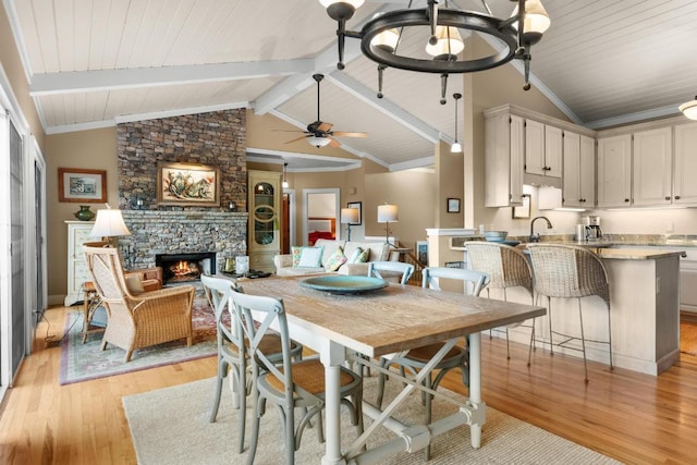 dining room with a fireplace, light wood-style flooring, a ceiling fan, wood ceiling, and baseboards