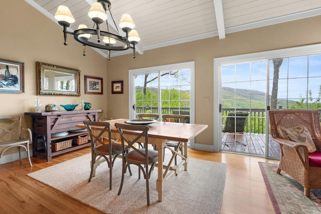 dining area with a chandelier, light wood-style flooring, a mountain view, crown molding, and wooden ceiling