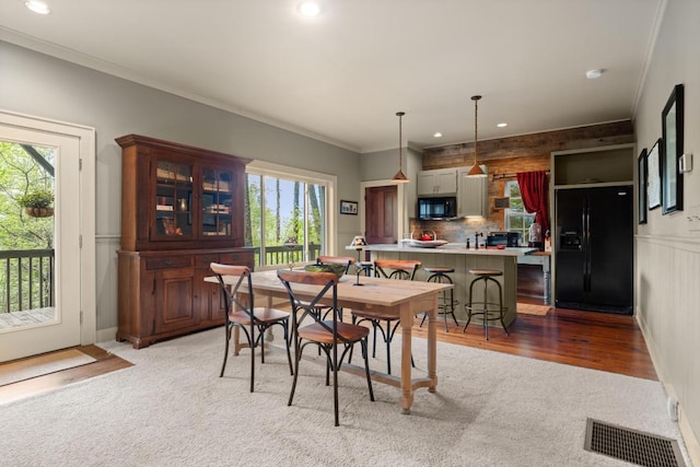 dining space with healthy amount of natural light, recessed lighting, crown molding, light colored carpet, and wainscoting
