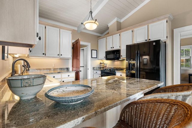 kitchen with black appliances, a peninsula, dark stone counters, white cabinets, and a breakfast bar area