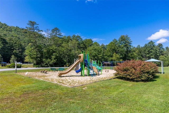 community playground featuring a lawn and a wooded view