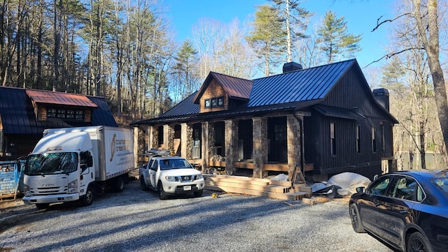 view of side of property with a standing seam roof, a chimney, metal roof, and stone siding
