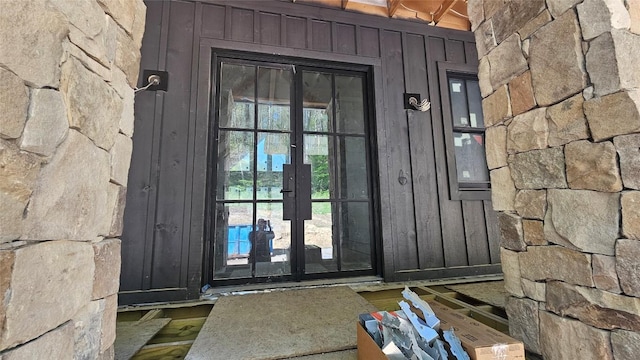 property entrance with french doors, board and batten siding, and stone siding