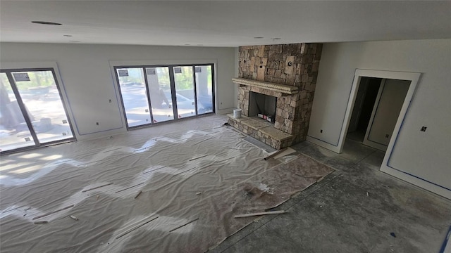 unfurnished living room with plenty of natural light and a stone fireplace