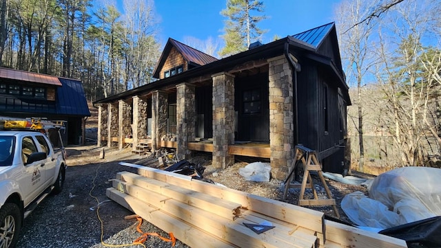 view of home's exterior featuring a standing seam roof, a porch, metal roof, and stone siding
