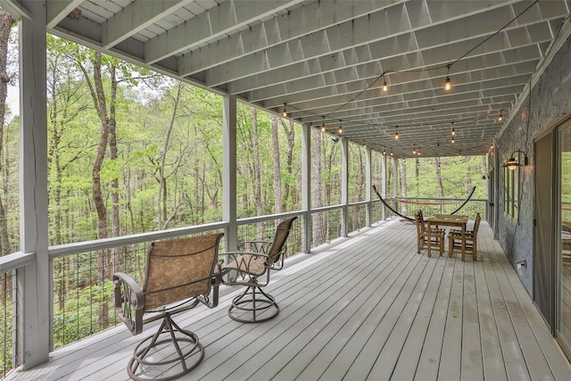 deck with a wooded view and outdoor dining space