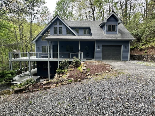 view of front of property with an attached garage, a shingled roof, covered porch, and gravel driveway