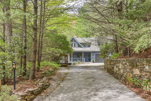 view of front of home with a porch, concrete driveway, and a chimney