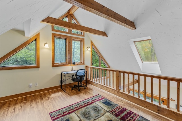 office space with lofted ceiling with skylight, wood finished floors, and a healthy amount of sunlight