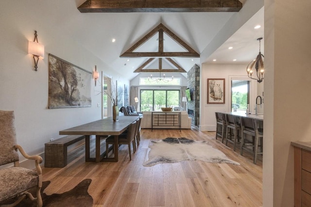 dining area with a chandelier, plenty of natural light, beam ceiling, light wood-style flooring, and high vaulted ceiling