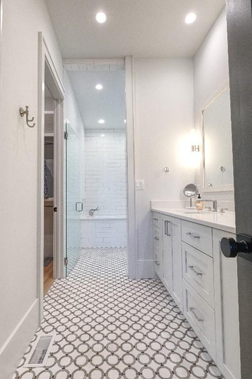 bathroom featuring tiled bath, recessed lighting, vanity, a tile shower, and baseboards