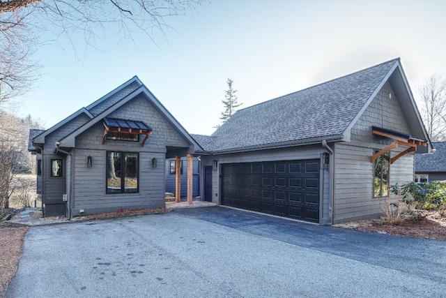 view of front of home with a garage, driveway, and a shingled roof