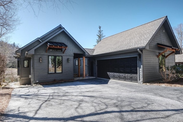 view of front of house with driveway, roof with shingles, and an attached garage