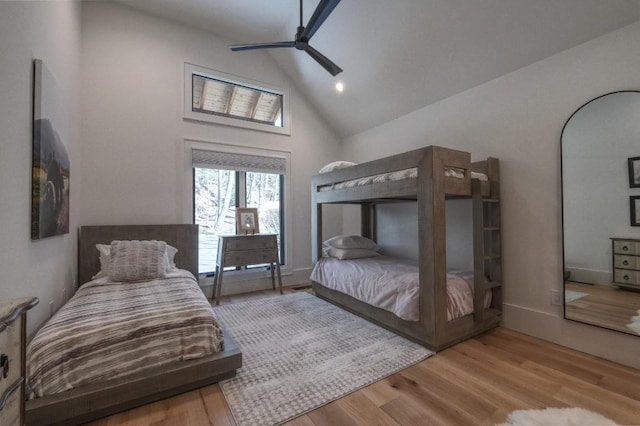 bedroom with a ceiling fan, wood finished floors, baseboards, and high vaulted ceiling