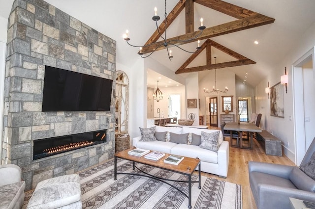 living area with light wood finished floors, baseboards, a chandelier, beamed ceiling, and a stone fireplace