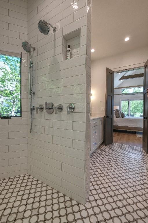 ensuite bathroom featuring a tile shower and recessed lighting