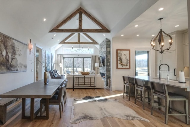 dining area with light wood-style flooring, recessed lighting, high vaulted ceiling, and a chandelier