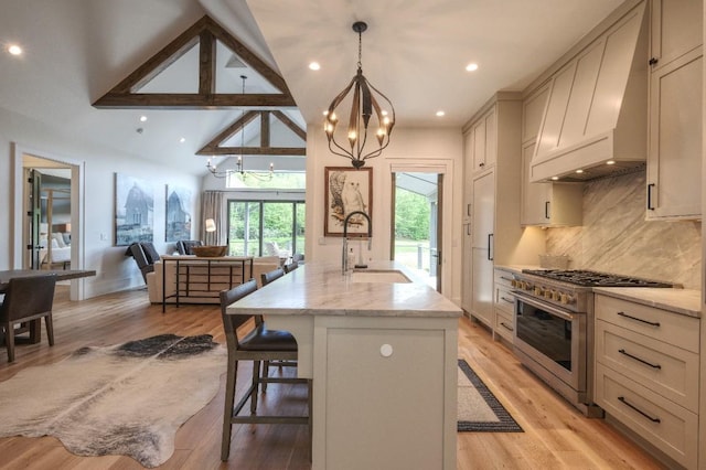 kitchen with high end stove, custom range hood, a sink, a chandelier, and a breakfast bar