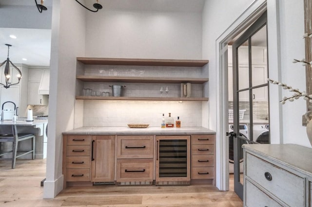 bar featuring beverage cooler, light wood-style floors, pendant lighting, a dry bar, and tasteful backsplash