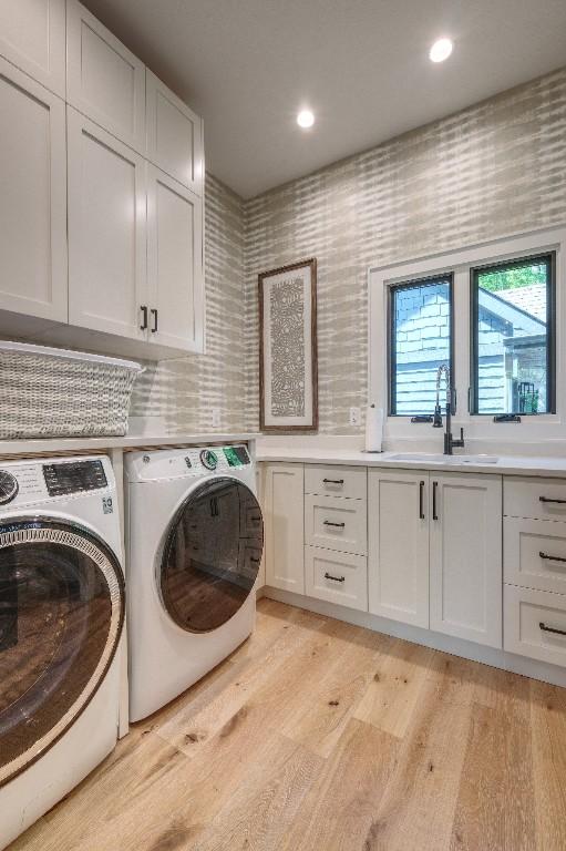 laundry area with cabinet space, washing machine and clothes dryer, light wood-type flooring, and recessed lighting