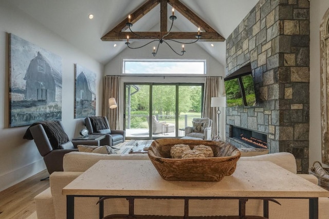 living area with a stone fireplace, wood finished floors, a chandelier, high vaulted ceiling, and beamed ceiling