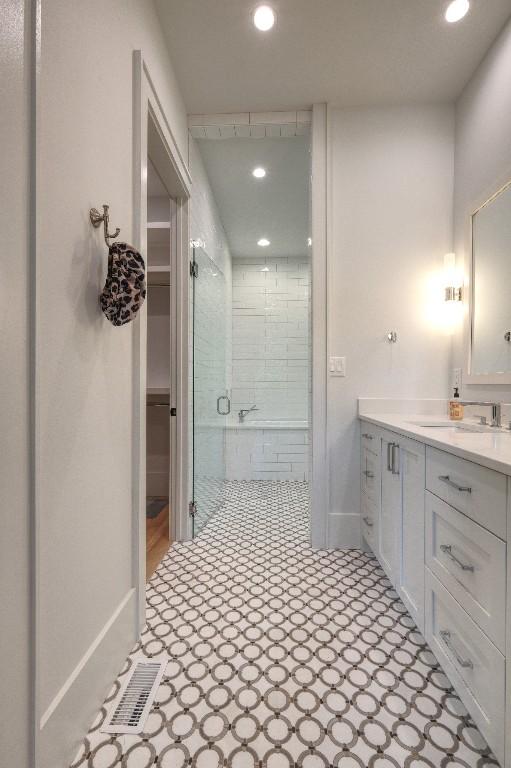 bathroom featuring recessed lighting, baseboards, a shower stall, vanity, and a walk in closet