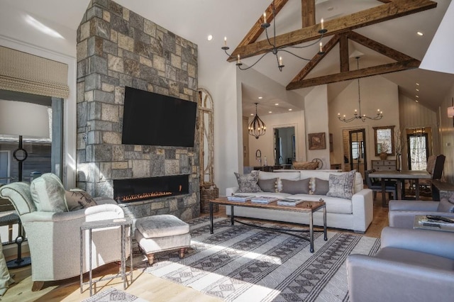 living room with beam ceiling, high vaulted ceiling, a notable chandelier, wood finished floors, and a fireplace