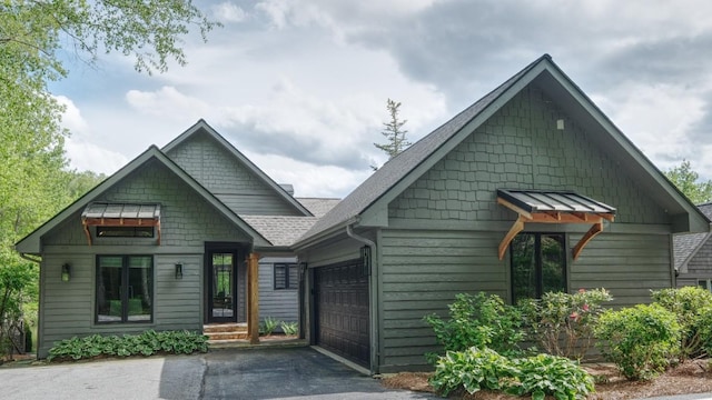 view of front of property with asphalt driveway, an attached garage, and roof with shingles