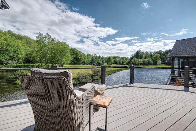 deck with a water view and view of wooded area
