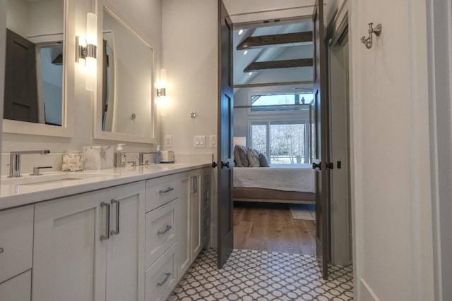 bathroom with a sink, beam ceiling, ensuite bath, and double vanity