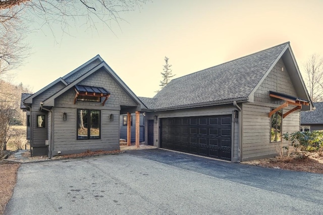 view of front facade with driveway, an attached garage, and roof with shingles