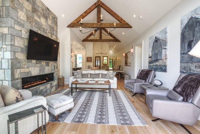 living room featuring a chandelier, a fireplace, wood finished floors, and lofted ceiling