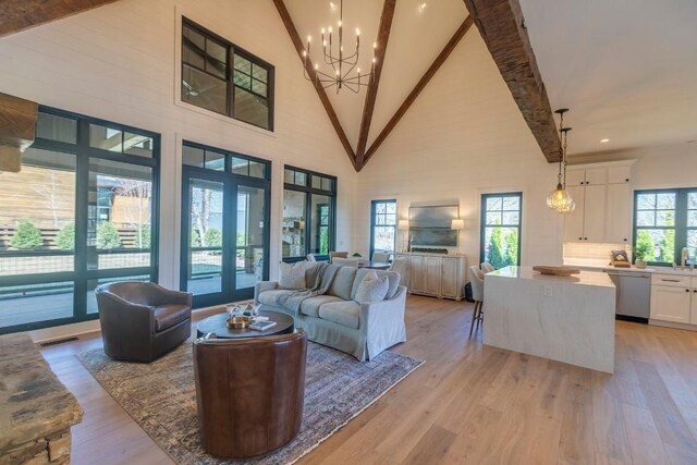 unfurnished living room with high vaulted ceiling, french doors, beamed ceiling, and light wood-type flooring