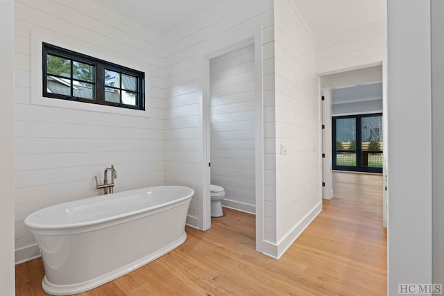 bathroom featuring a washtub, wood-type flooring, and toilet