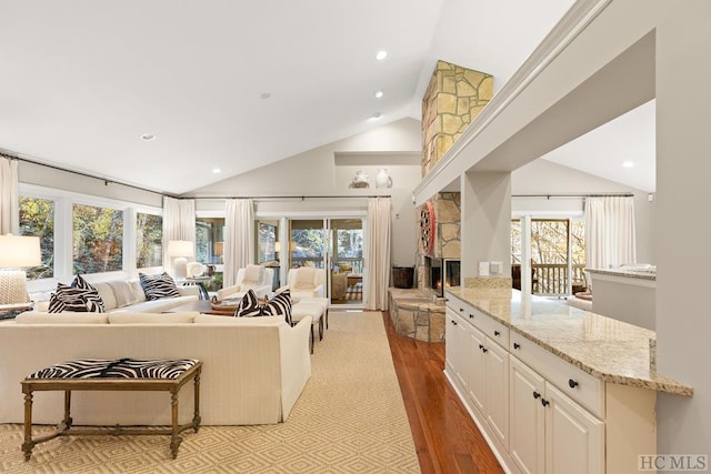 kitchen featuring a stone fireplace, light stone countertops, a kitchen breakfast bar, sink, and kitchen peninsula