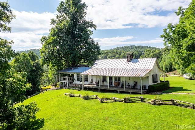 rear view of house featuring a lawn and a deck