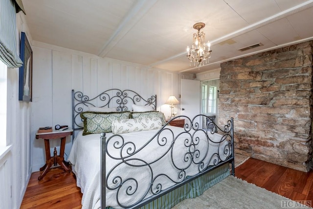 bedroom featuring hardwood / wood-style flooring, an inviting chandelier, and beam ceiling