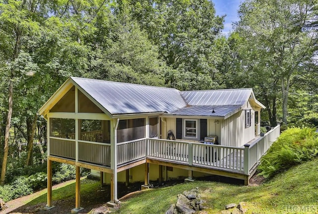 rear view of house featuring a sunroom and a lawn