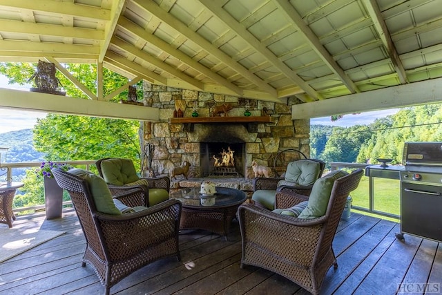 wooden terrace with grilling area and an outdoor stone fireplace