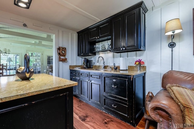 bar with light stone countertops, sink, and dark hardwood / wood-style flooring