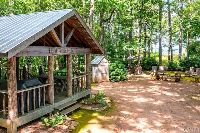 view of patio featuring an outdoor fire pit, a deck, and a storage shed