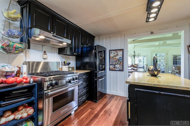 kitchen with high end range, light stone countertops, dark hardwood / wood-style flooring, and black refrigerator