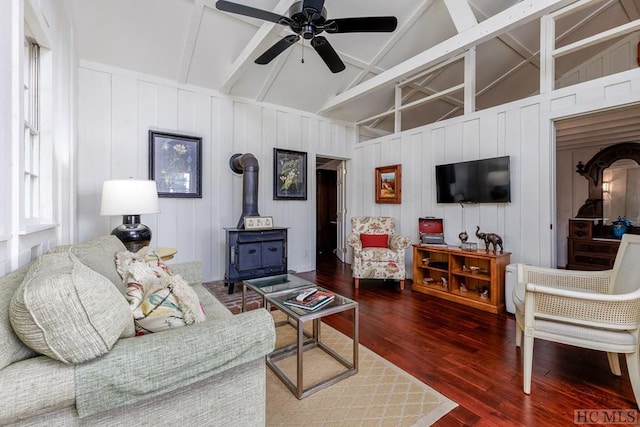 living room featuring ceiling fan, wood-type flooring, vaulted ceiling, and a wood stove