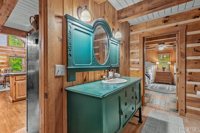 bathroom featuring wood walls, beam ceiling, and vanity