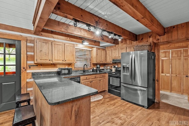 kitchen with light brown cabinets, sink, light wood-type flooring, wood walls, and black appliances