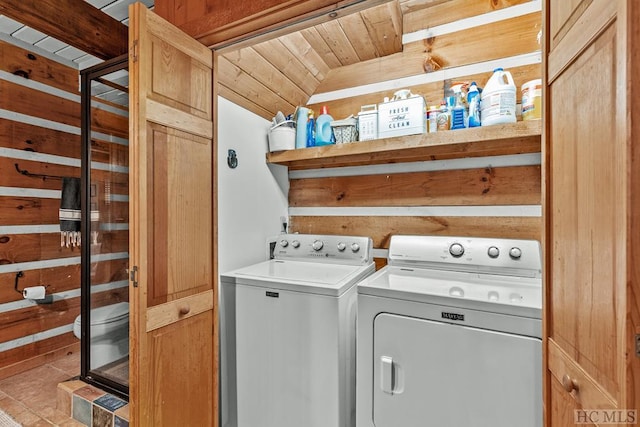 clothes washing area featuring wooden ceiling, washing machine and dryer, and wooden walls