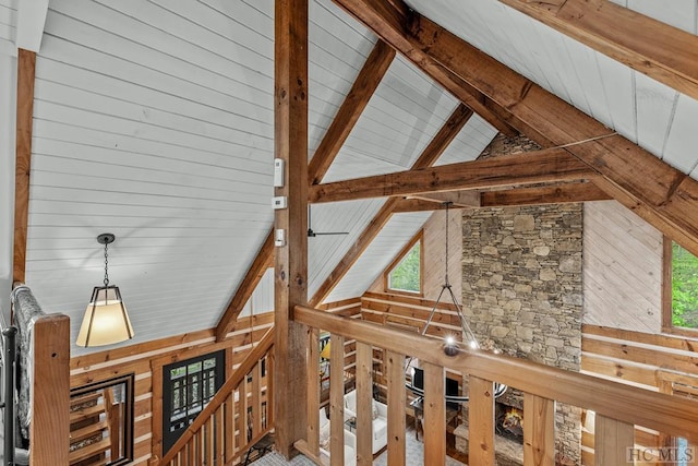 interior space featuring a healthy amount of sunlight, wooden walls, beam ceiling, and high vaulted ceiling