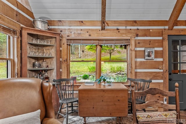 dining space with vaulted ceiling and wooden walls