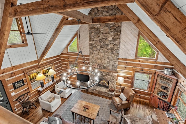 unfurnished living room featuring a stone fireplace, hardwood / wood-style floors, high vaulted ceiling, wooden walls, and beamed ceiling